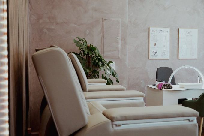 In einem Raum steht eine Reihe von Stühlen neben einem Tisch. Lavish Nails & Lashes