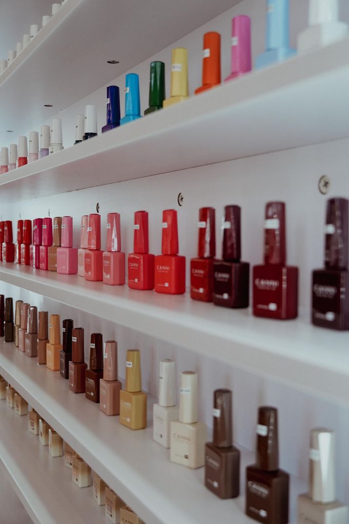 Eine Frau mit rosa Nägeln, dahinter ein Glastiegel mit rosa Pulver, Lavish Nails & Lashes