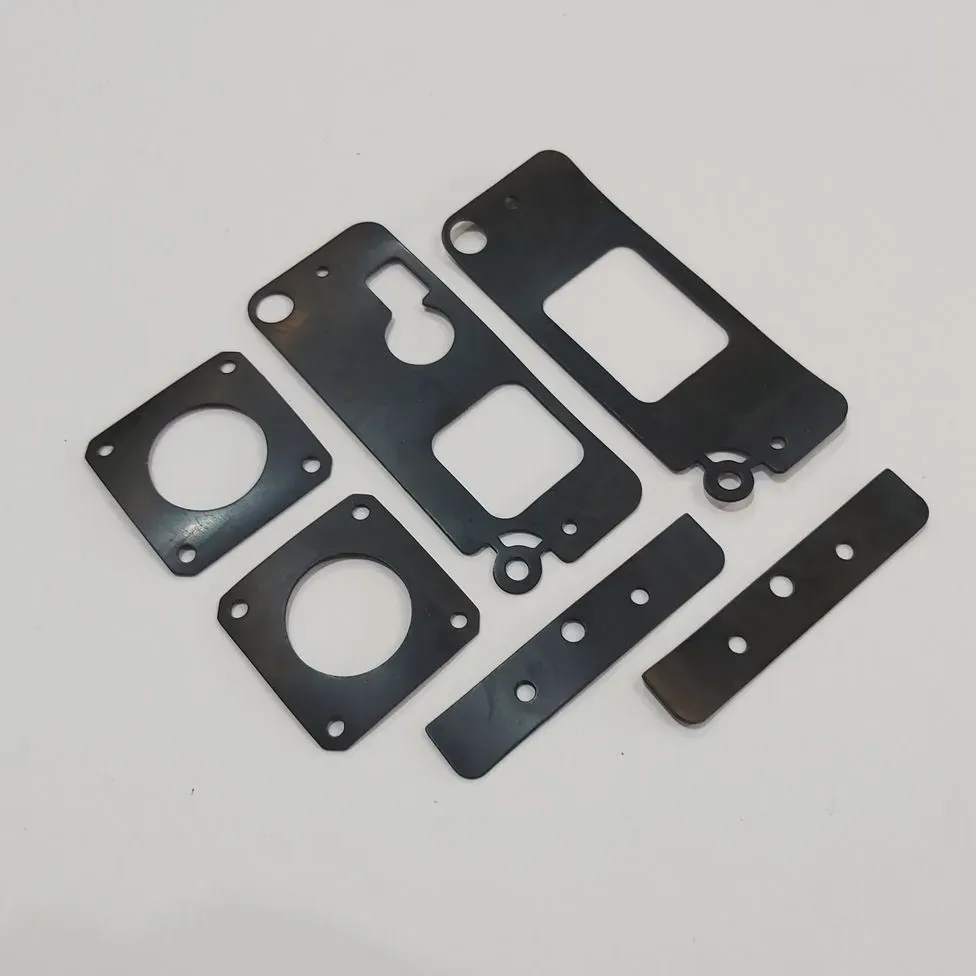 Un montón de piezas de metal con agujeros sobre una superficie blanca.