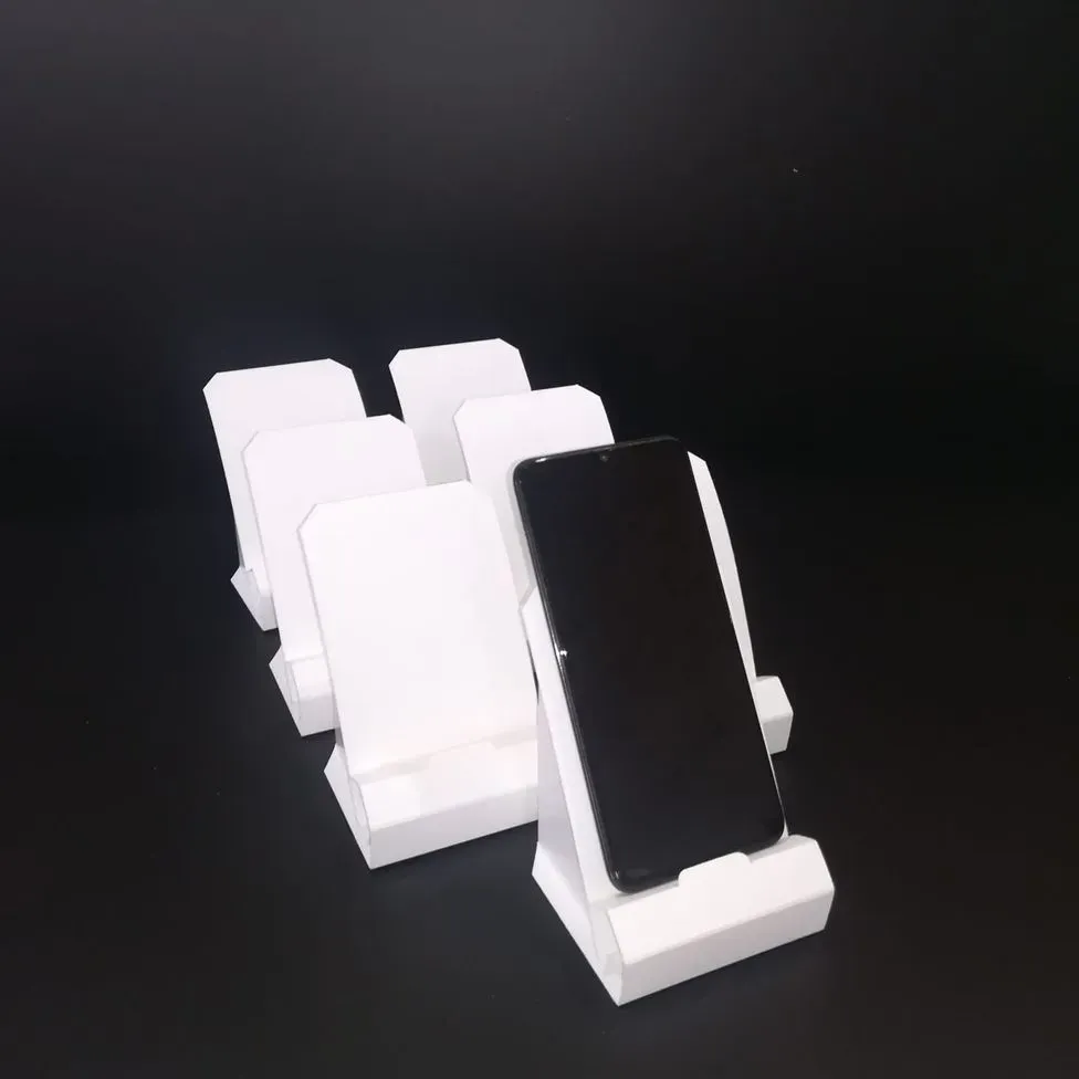 Un teléfono celular colocado encima de un soporte de teléfono blanco.