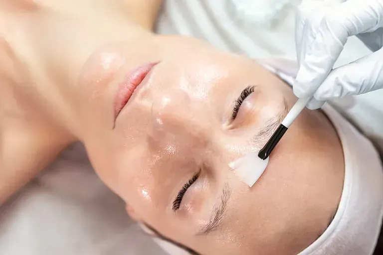 Una mujer está recibiendo un tratamiento facial con un cepillo en su cara.