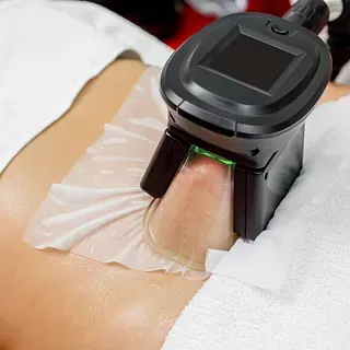 Una persona está acostada en una cama con una máquina sobre su estómago.