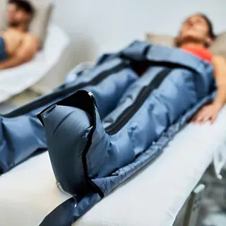 Un hombre está acostado en una cama con las piernas envueltas en una manta azul.