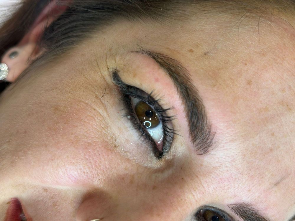 Un primer plano del rostro de una mujer con delineador de ojos y cejas.