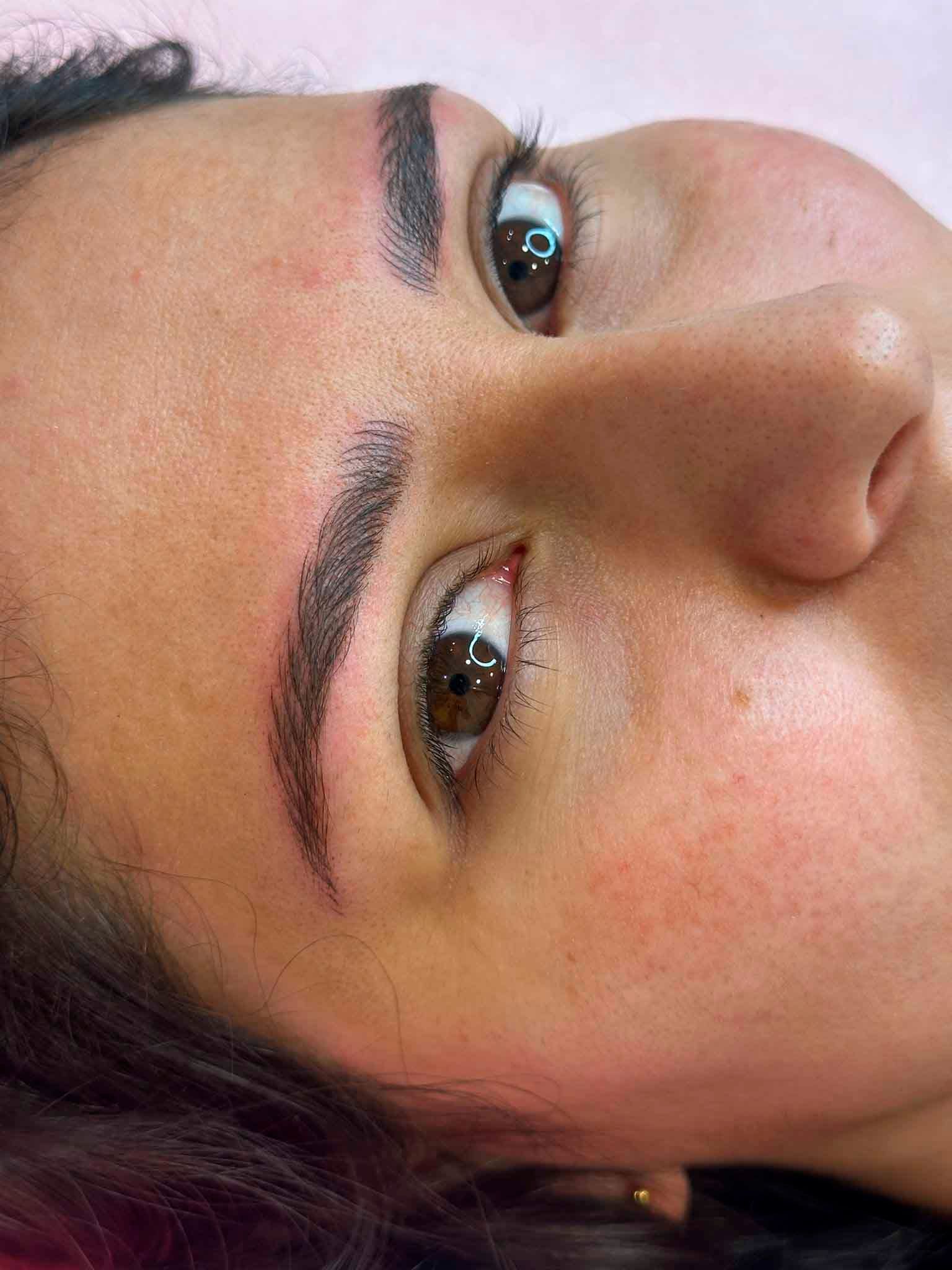 Un primer plano del rostro de una mujer con un tatuaje en las cejas.