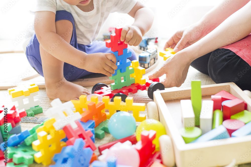 Kinder bauen mit bunten Bauklötzen auf dem Boden.