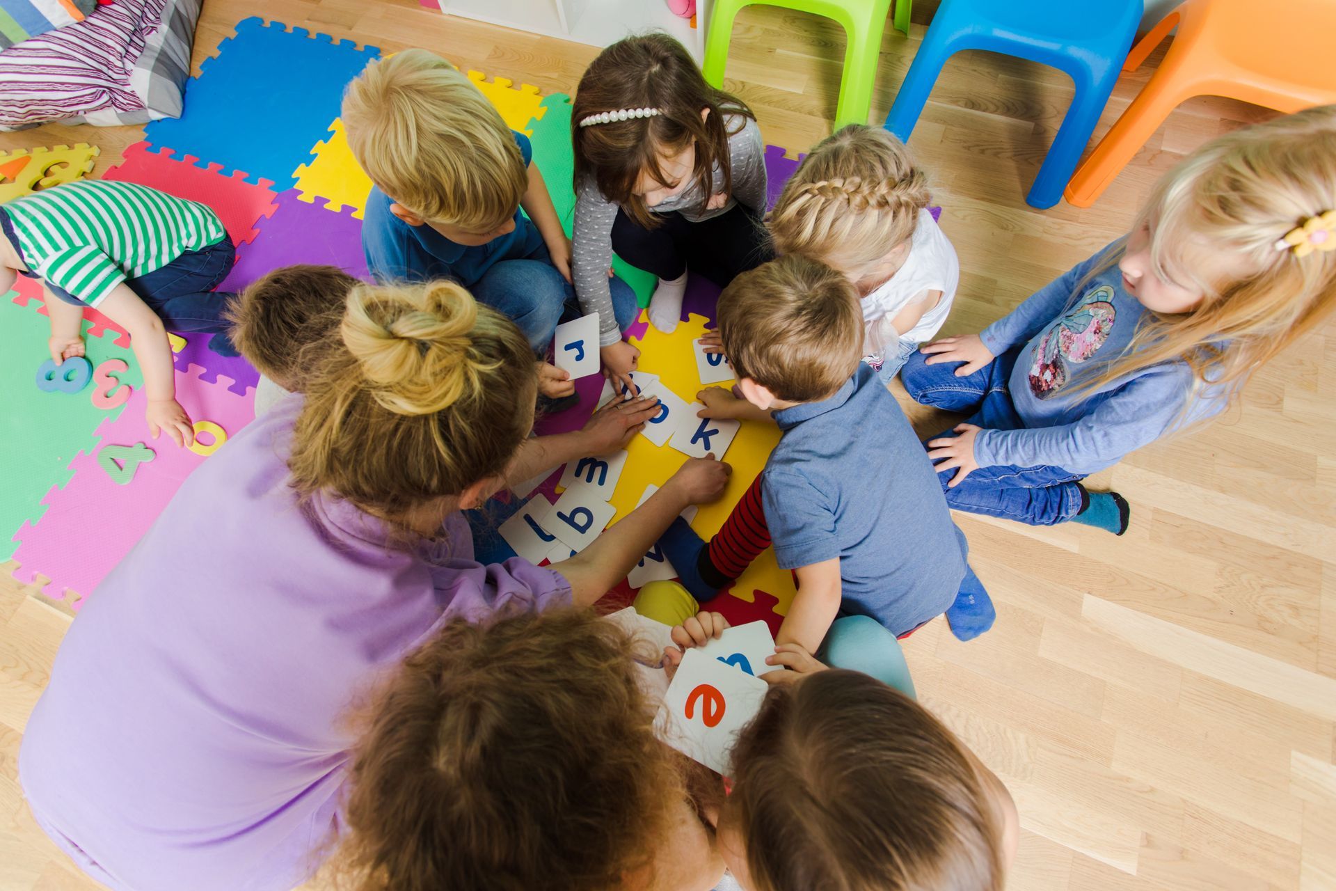 In einem hellen Klassenzimmer sassen die Kinder im Kreis auf dem Boden und spielten mit bunten Bauklötzen.