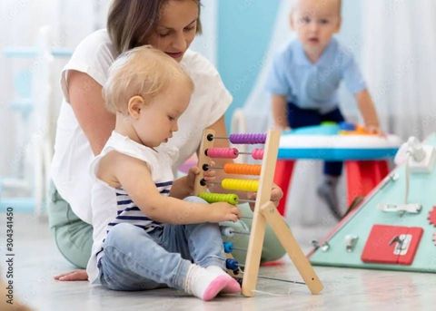 Erwachsener und Kind spielen in einem hellen Spielzimmer mit einem bunten Xylophon.