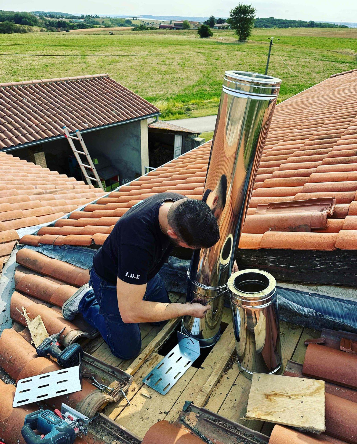Un ramoneur sur un toit qui vérifie un conduit