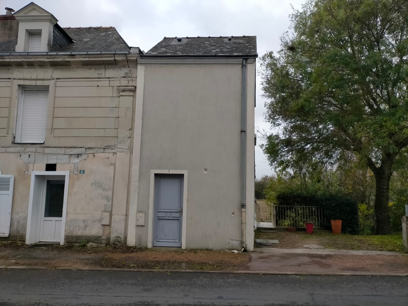 Côté d'une maison avec une porte d'entée bleue, mur sale.