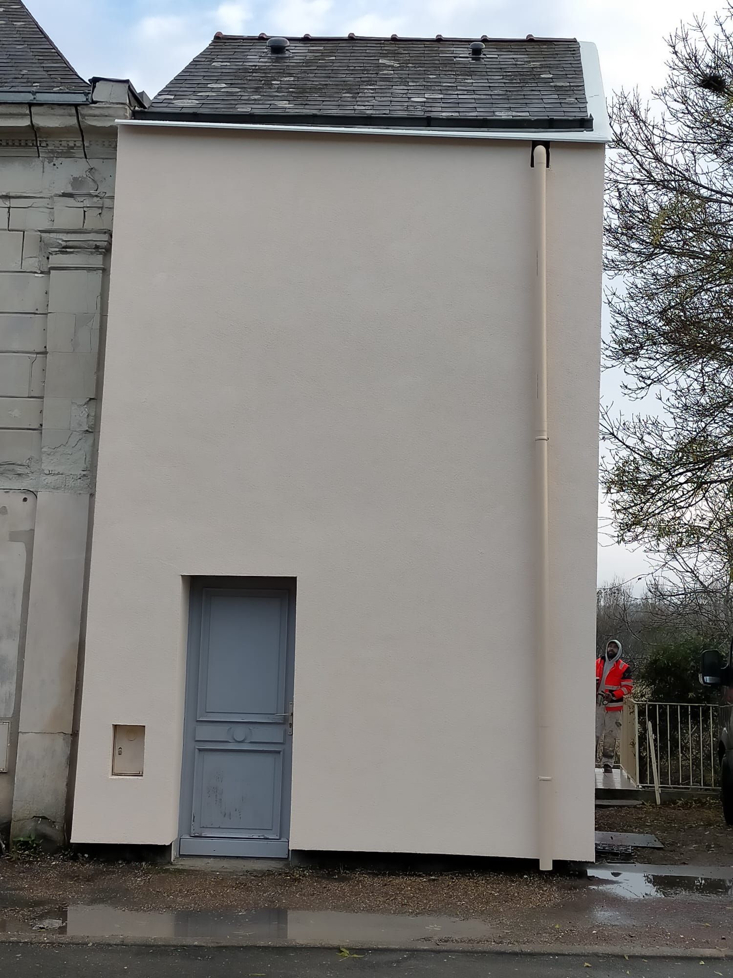 Côté d'une maison avec une porte d'entée bleue, mur rénové.