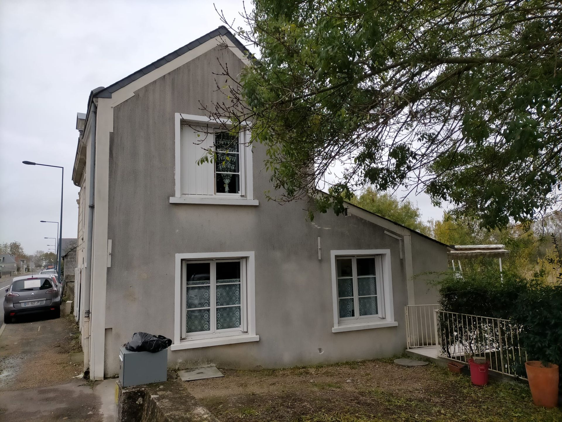 Maison à étage avec une façade grise et sale.