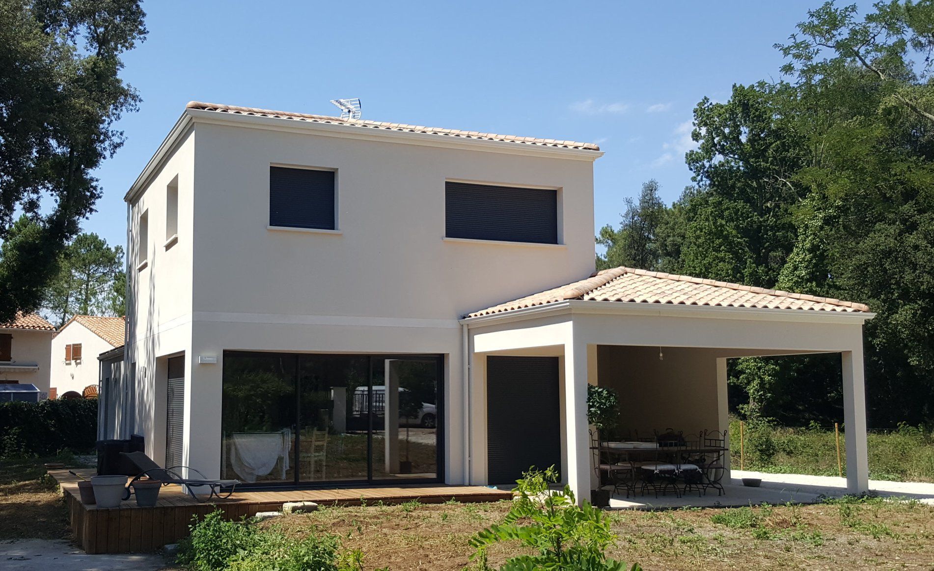 Maison blanche à étage avec patio couvert.