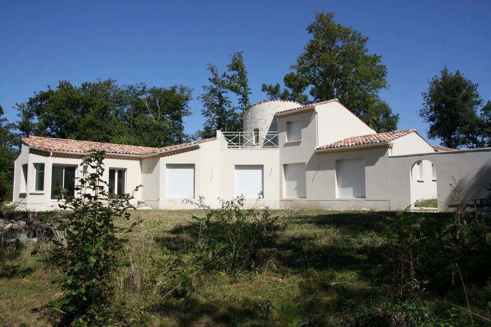 Maison blanche au toit de tuiles rouges, avec tour circulaire.
