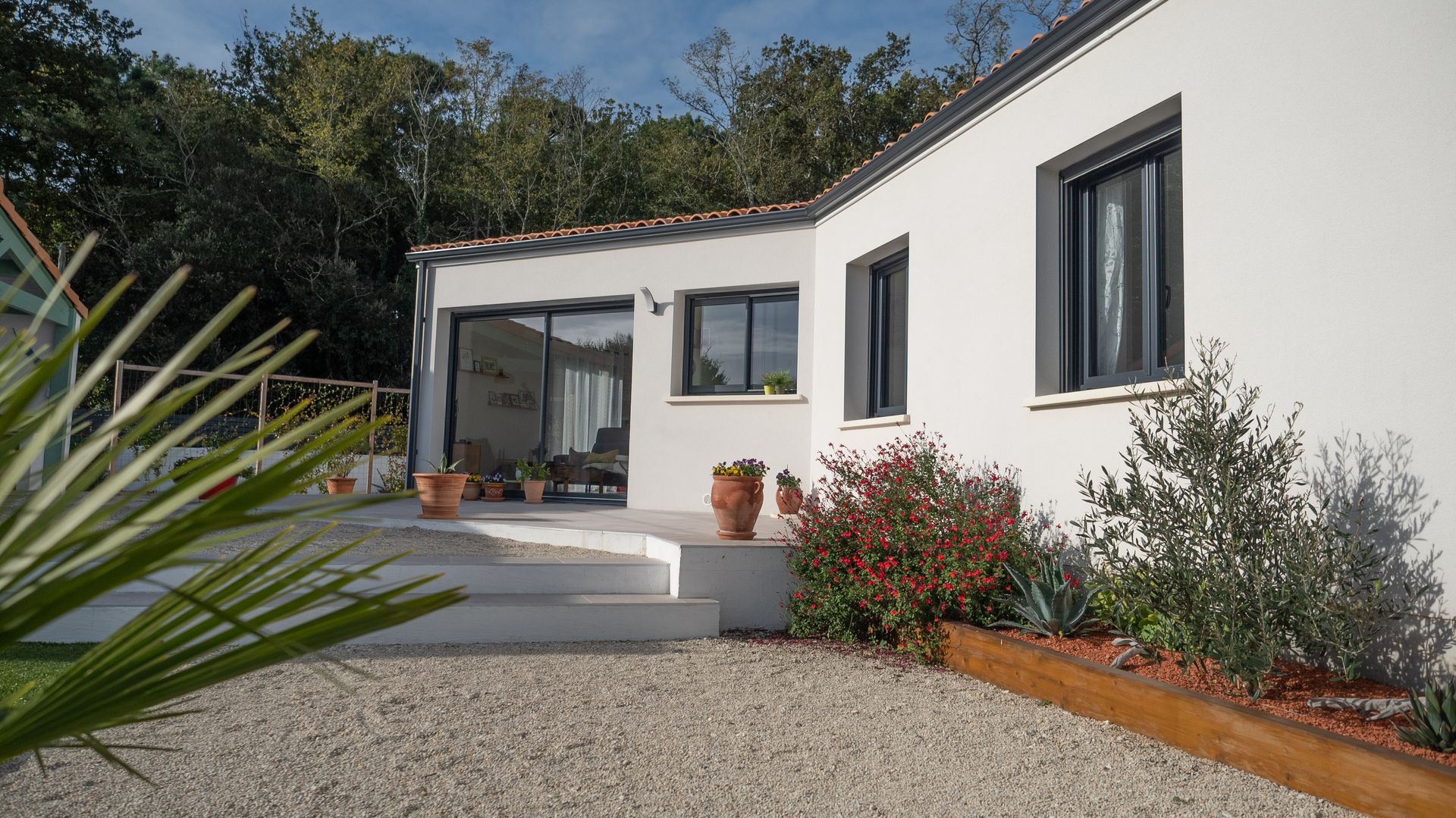 Maison blanche et cour gravillonnée.