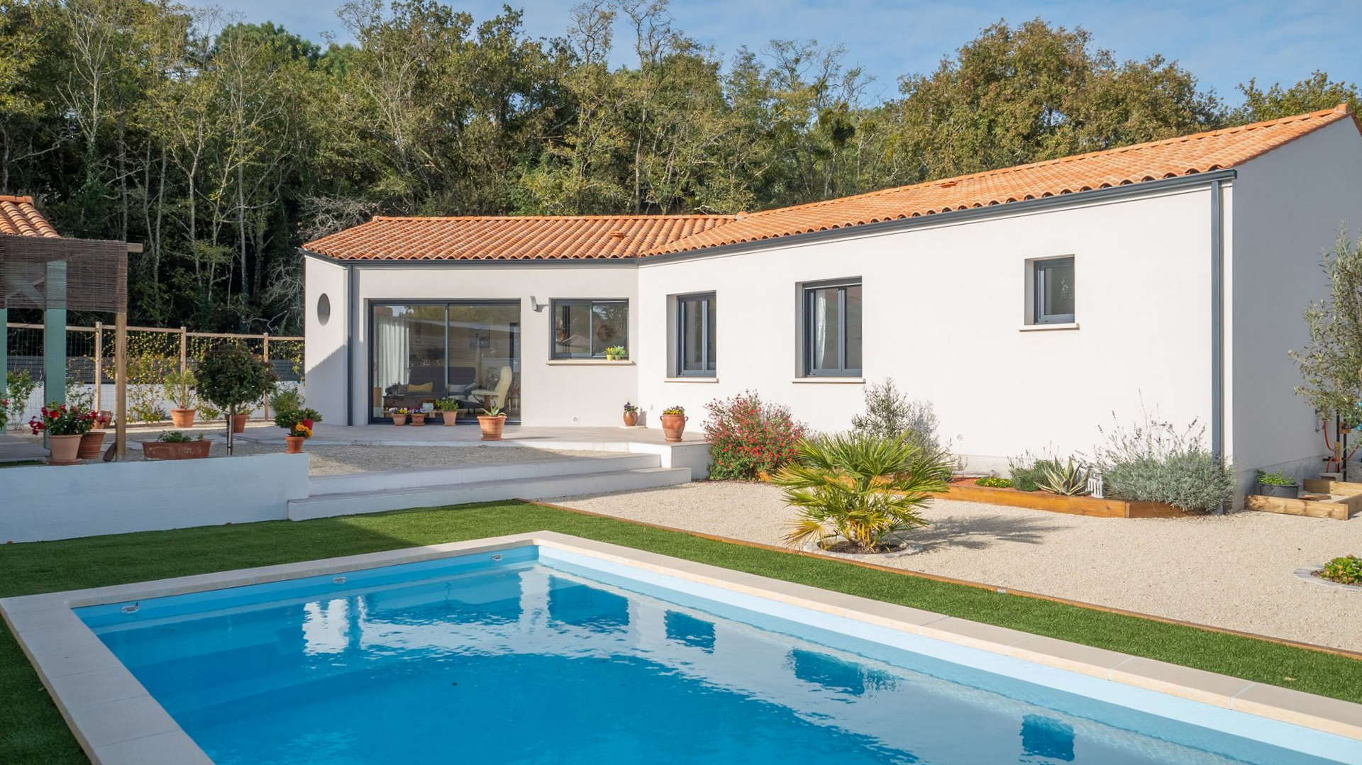 Maison blanche avec piscine dans un jardin.