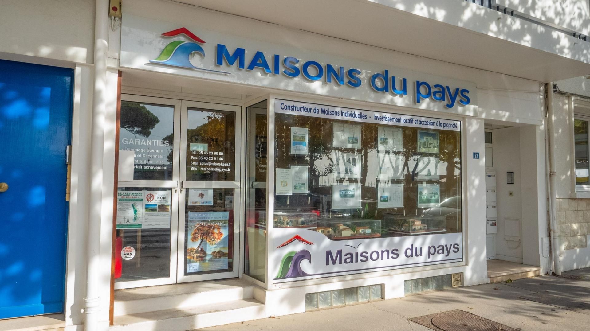 Façade de l'agence avec porte bleue, vitrines et logo.