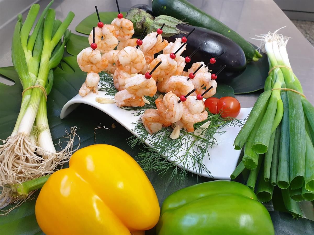 Ein weißer Teller mit Garnelen und Gemüse auf einem Tisch