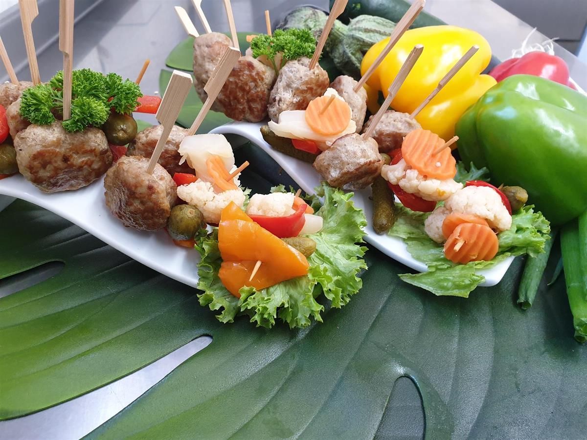 Ein Teller mit Fleischbällchen und Gemüse am Spieß