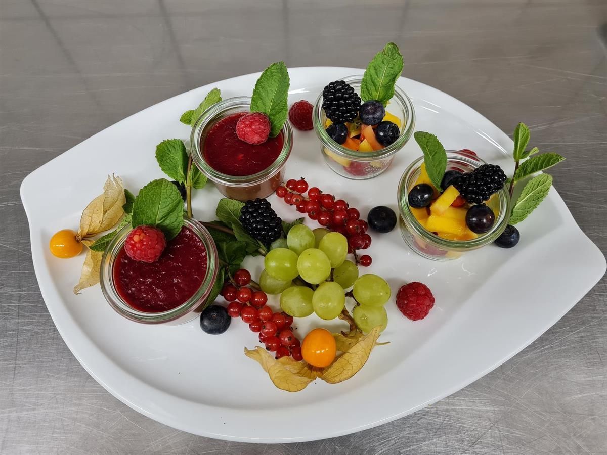 Ein weißer Teller mit verschiedenen Früchten und Saucen