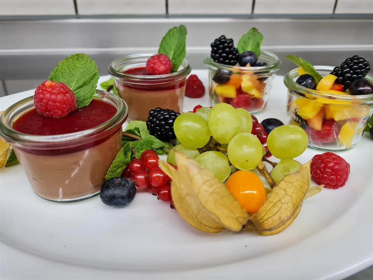 Ein weißer Teller mit Desserts und Obst auf einem Tisch.