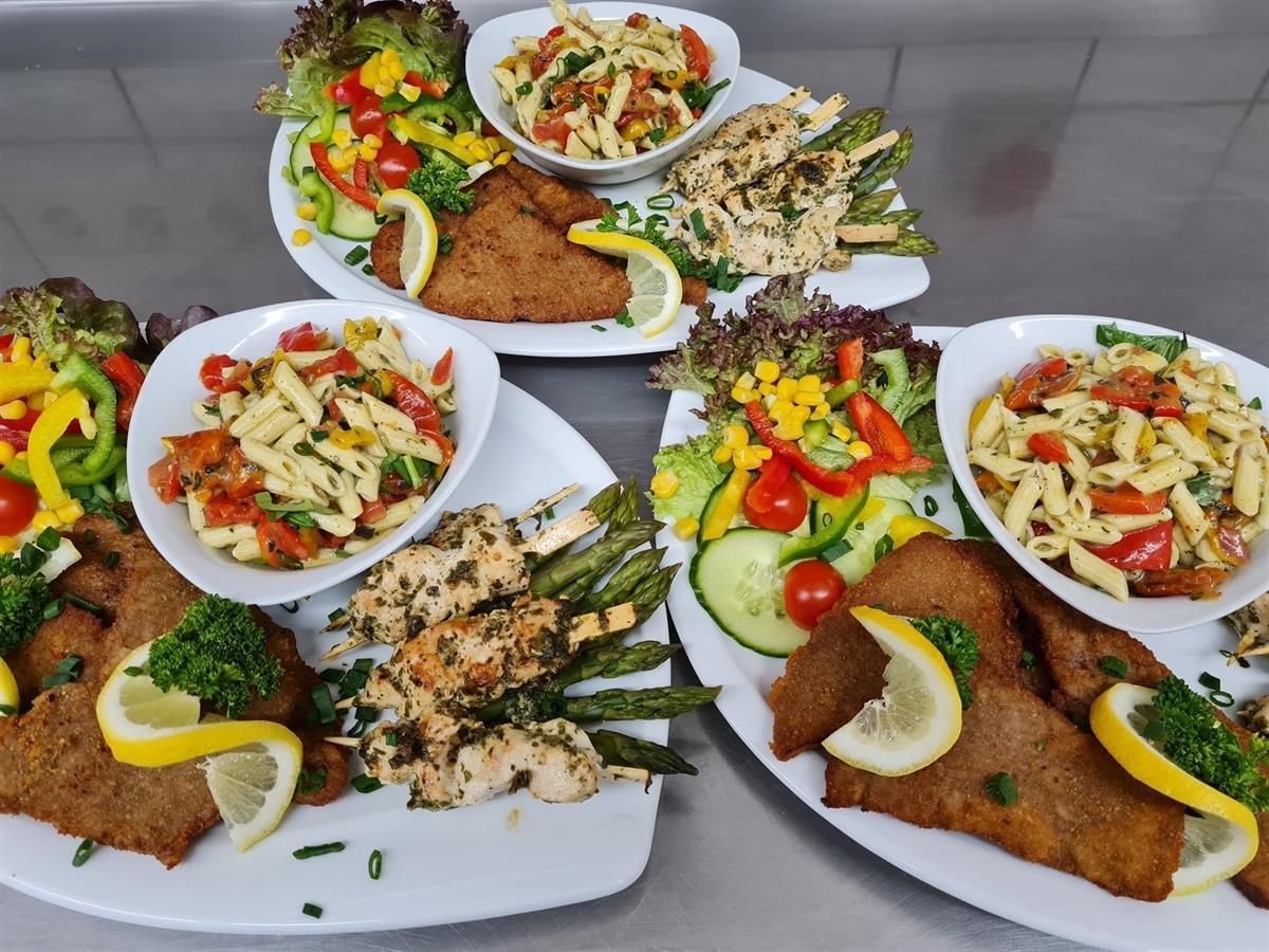 Ein Tisch mit Tellern voller Essen, darunter Fleisch und Gemüse