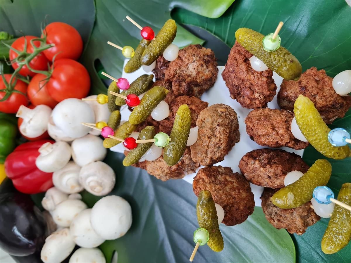 Ein Teller mit Fleischbällchen und Gurken am Spieß