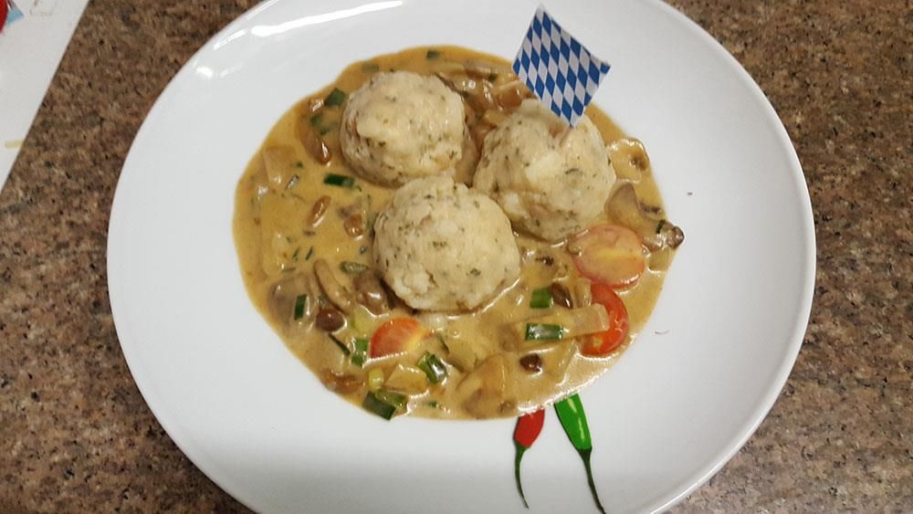 Ein weißer Teller mit Soße und Knödeln auf einem Tisch.