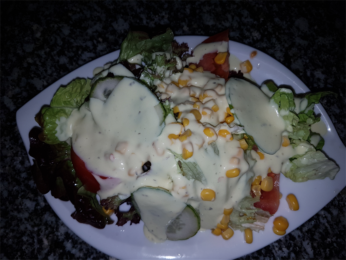 Ein weißer Teller mit einem Salat mit Mais und Tomaten