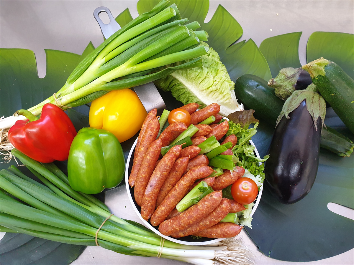 Eine Pfanne gefüllt mit Würstchen und Gemüse auf einem Tisch