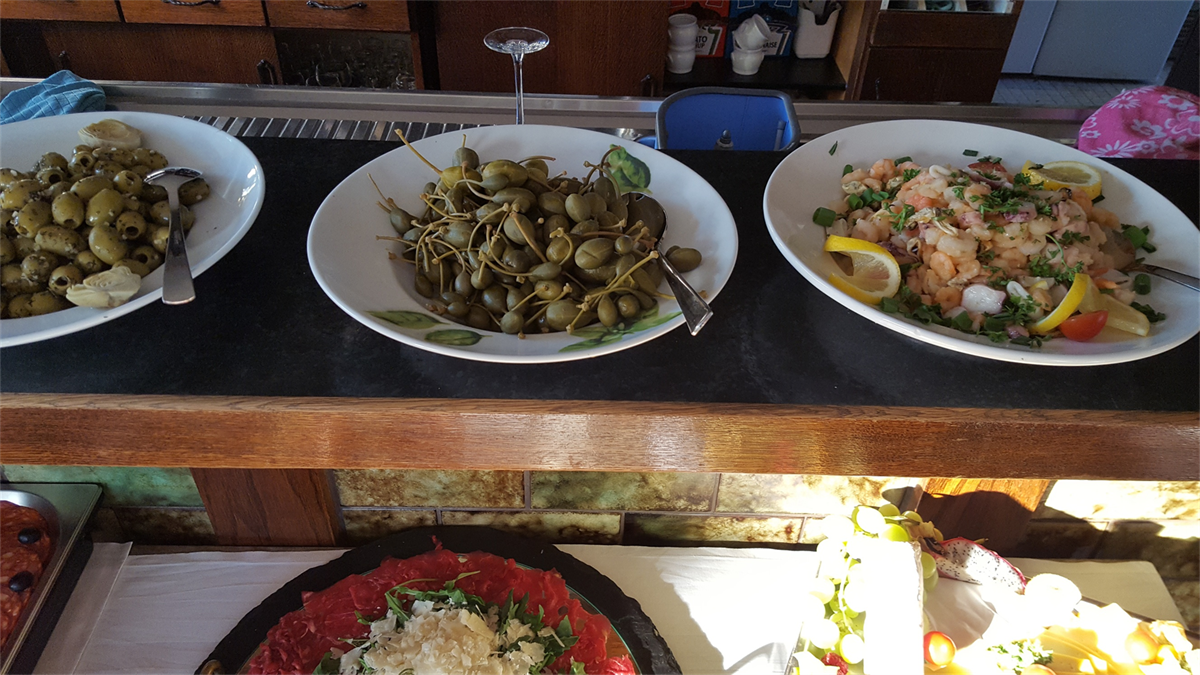 Drei Teller mit Essen stehen auf einem Tisch, darunter Oliven