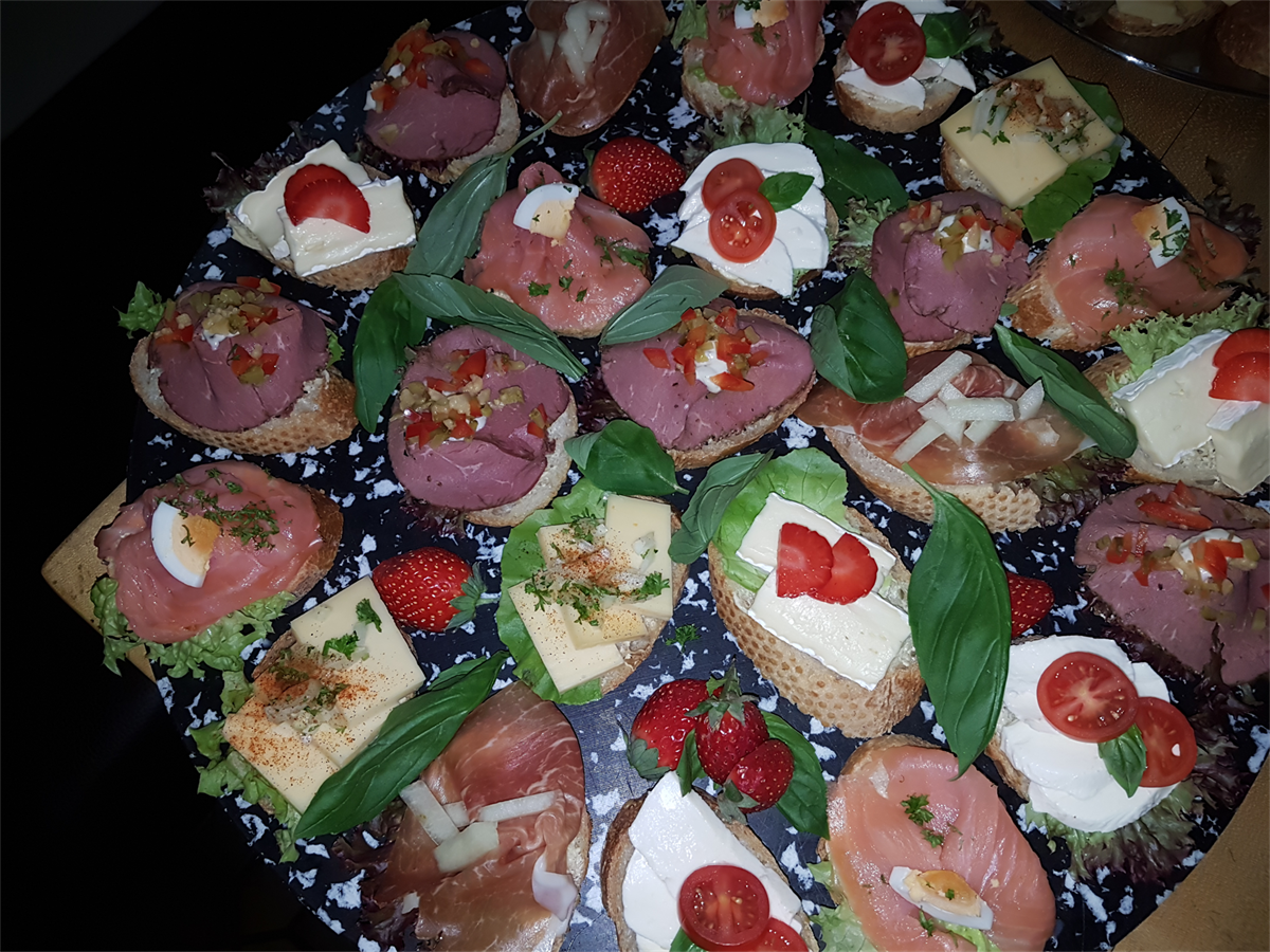 Ein Tisch mit einer Auswahl an Speisen, darunter Sandwiches und Erdbeeren