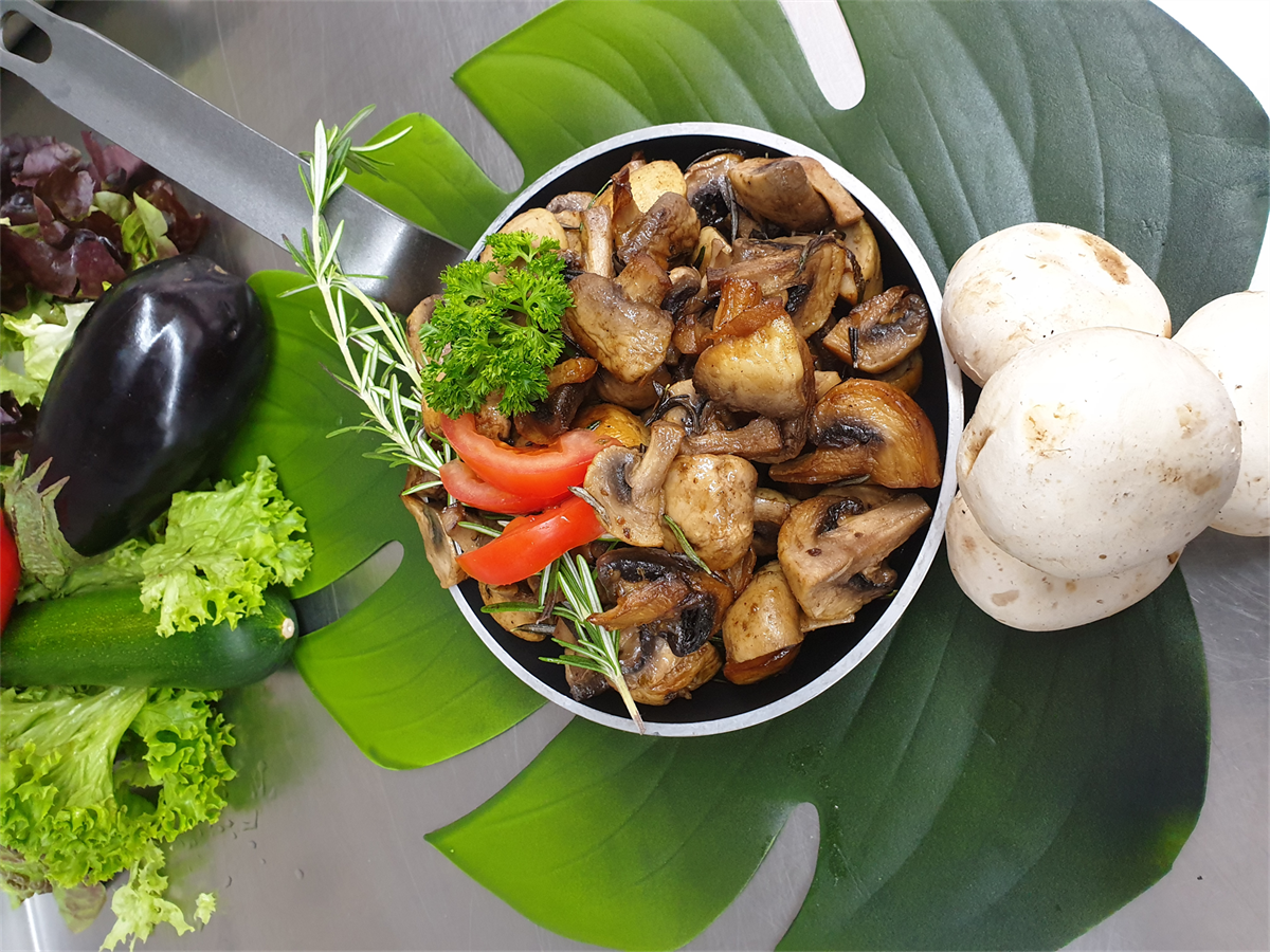 Eine Schüssel mit Pilzen und Gemüse auf einem Blatt