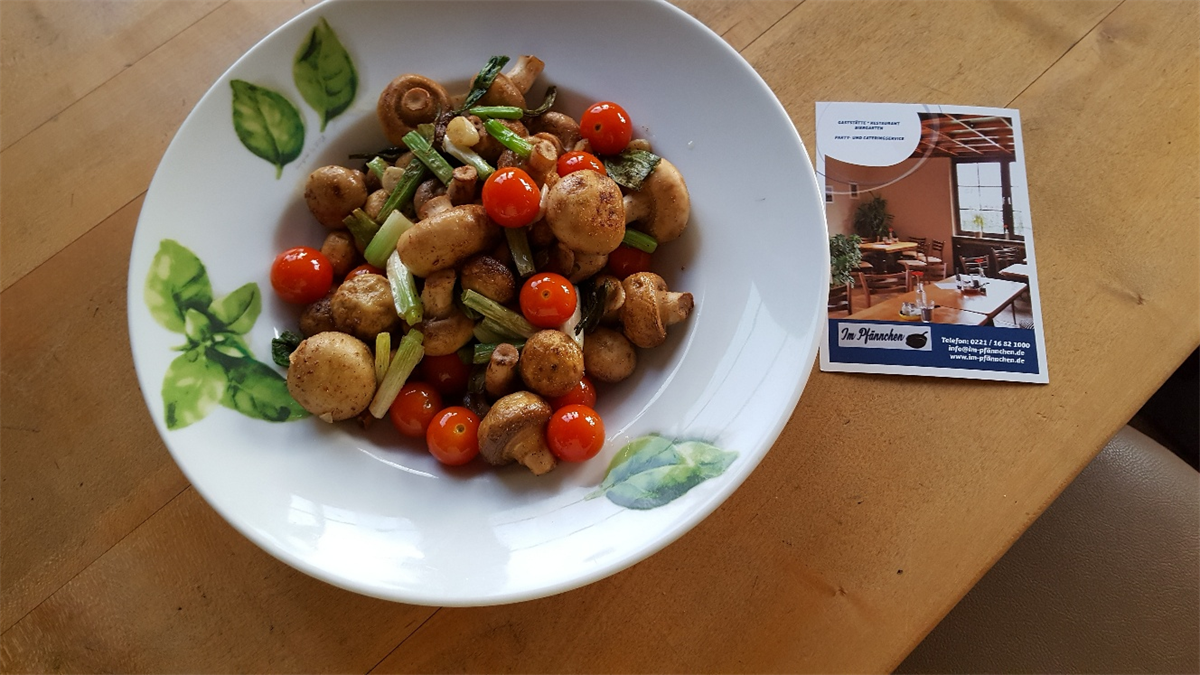 Eine Schüssel mit Pilzen und Tomaten auf einem Holztisch