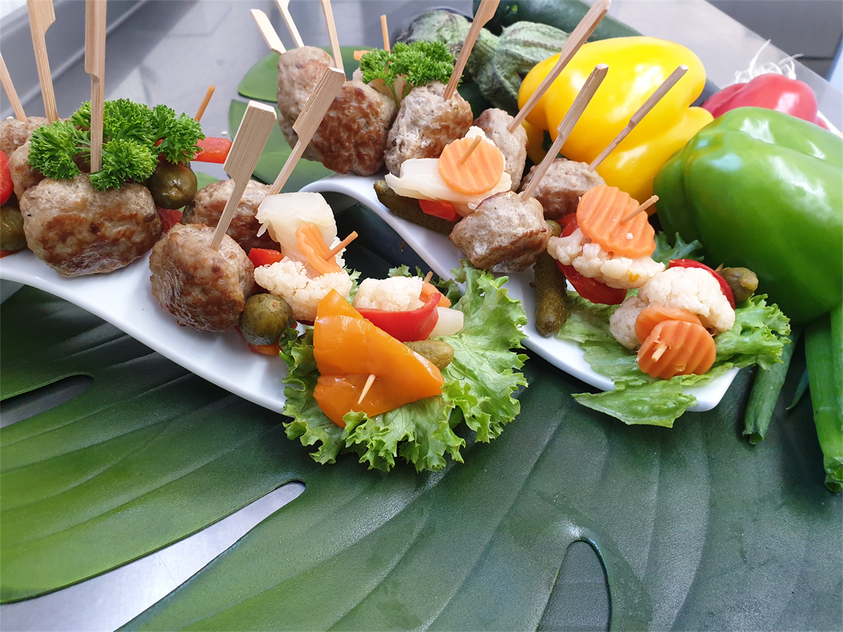 Ein Teller mit Fleischbällchen und Gemüse am Spieß