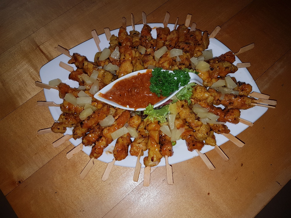 Ein weißer Teller mit Hähnchenspießen und Dip-Sauce