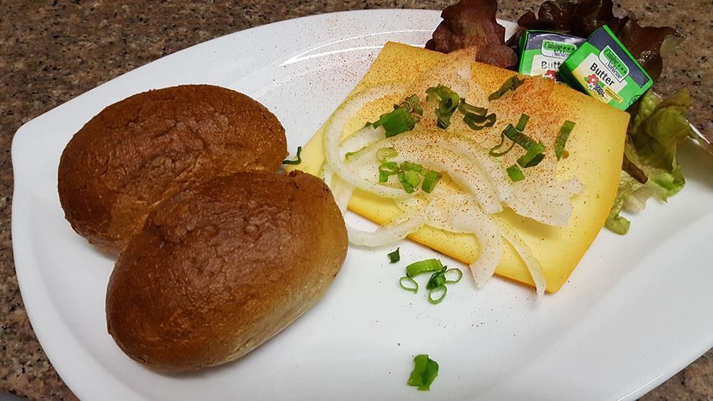 Ein weißer Teller mit Brot, Käse und Zwiebeln