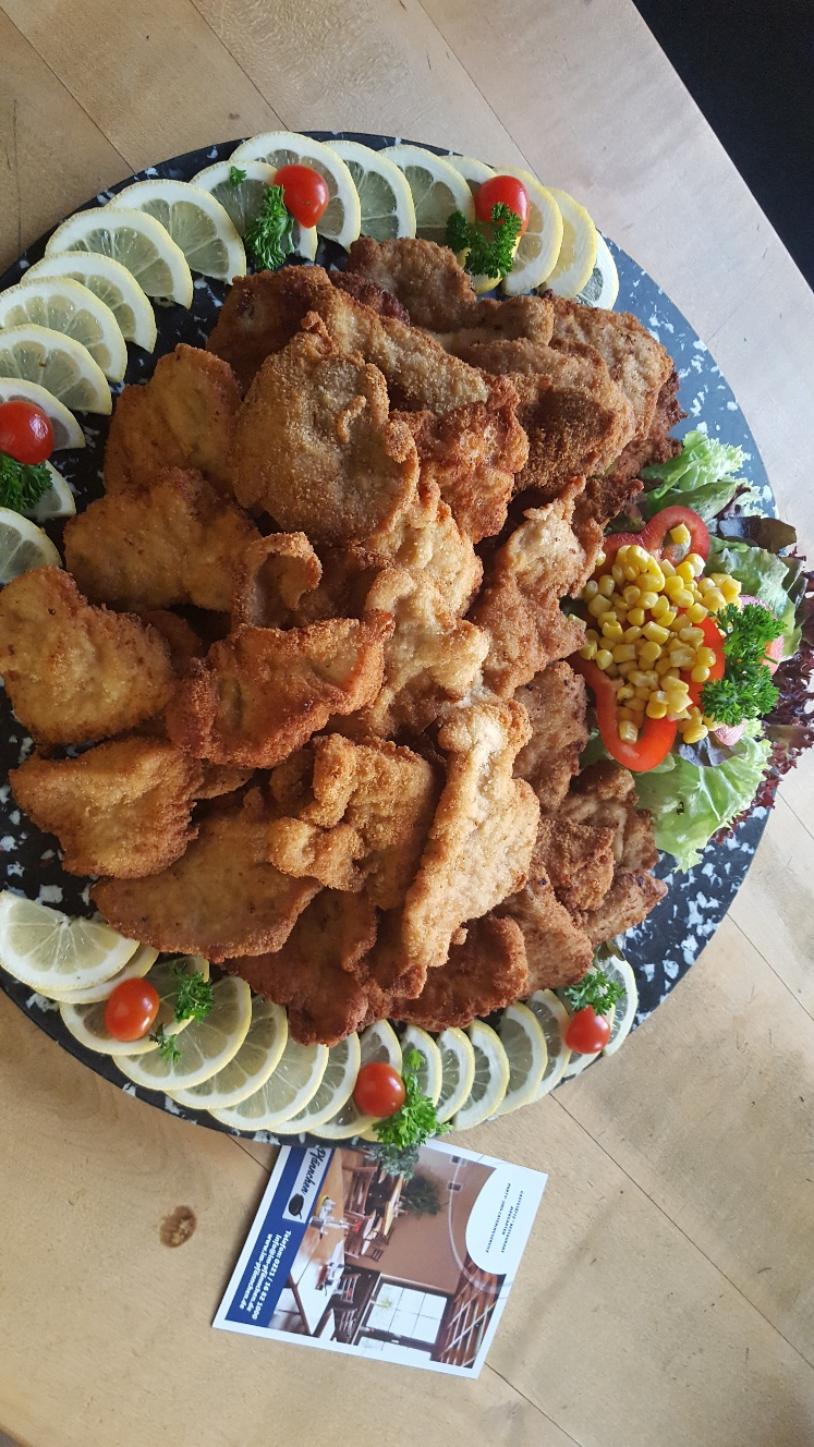 Ein Teller mit frittiertem Essen, Zitronenscheiben und Gemüse auf einem Holztisch.