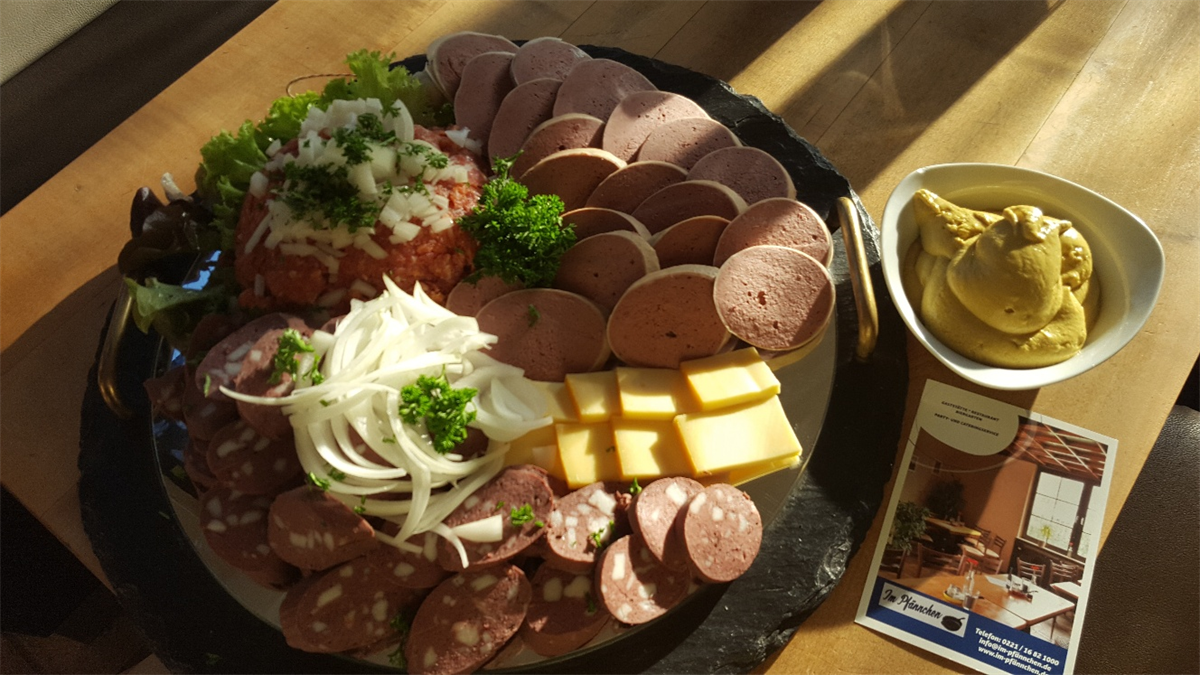 Ein Teller mit Fleisch und Käse neben einer Schüssel Senf