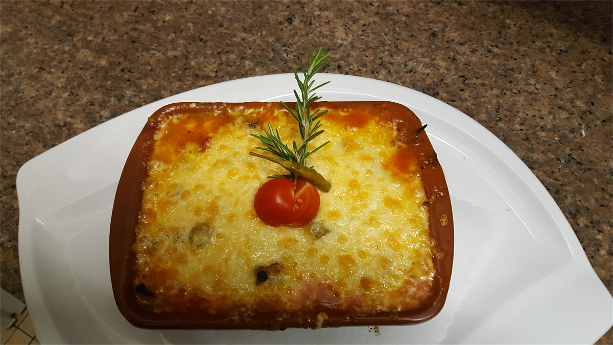 Ein weißer Teller mit einer Auflaufform und einer Tomate darauf.