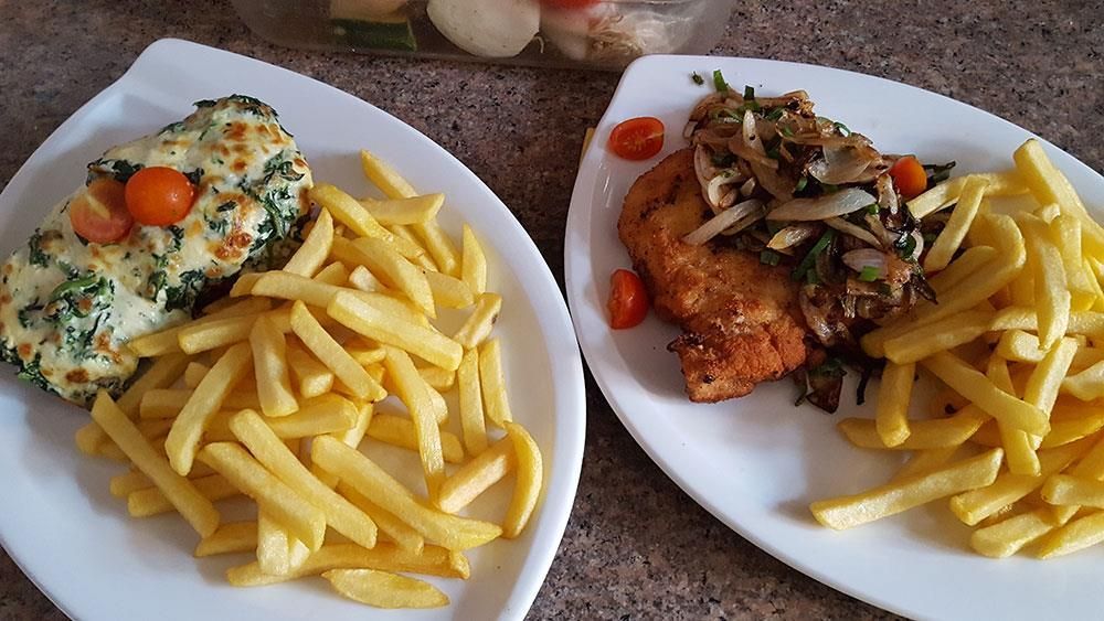 Zwei Teller mit Pommes Frites und Fleisch auf einem Tisch.