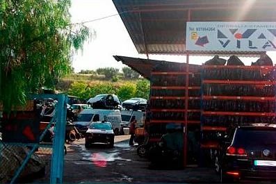 Hay muchos coches aparcados delante de un cartel que dice vila