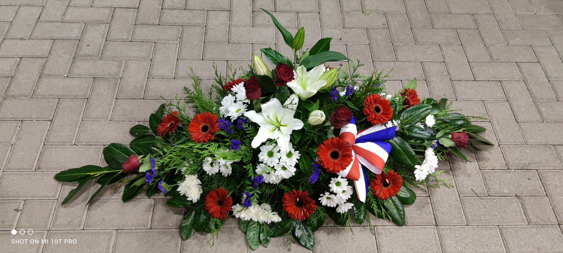 Composition florale pour deuil, devant de tombe avec noeud ruban tricolore