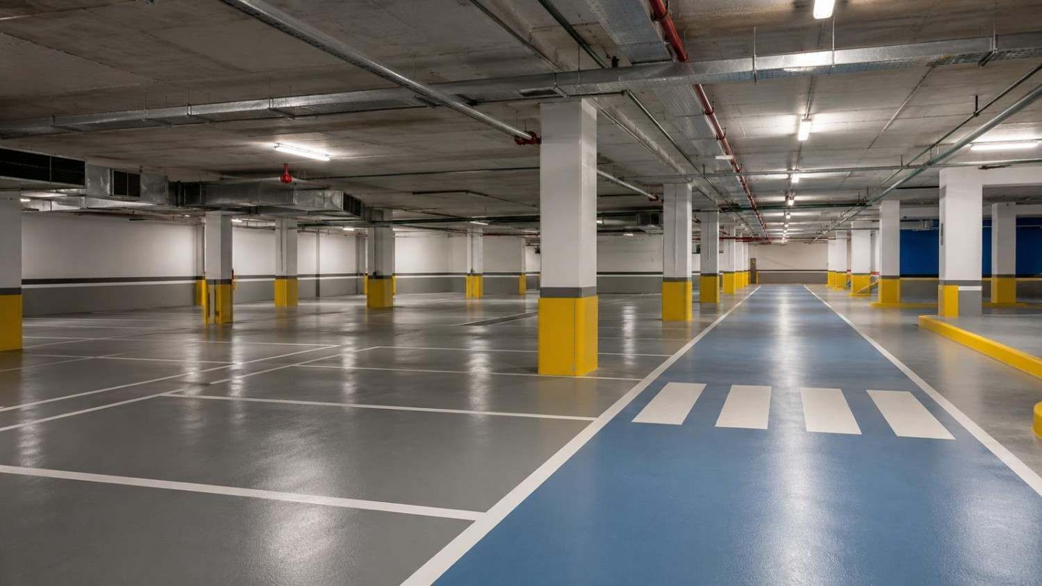 Un trabajador con una camisa color turquesa alisa un suelo blanco en una habitación vacía.