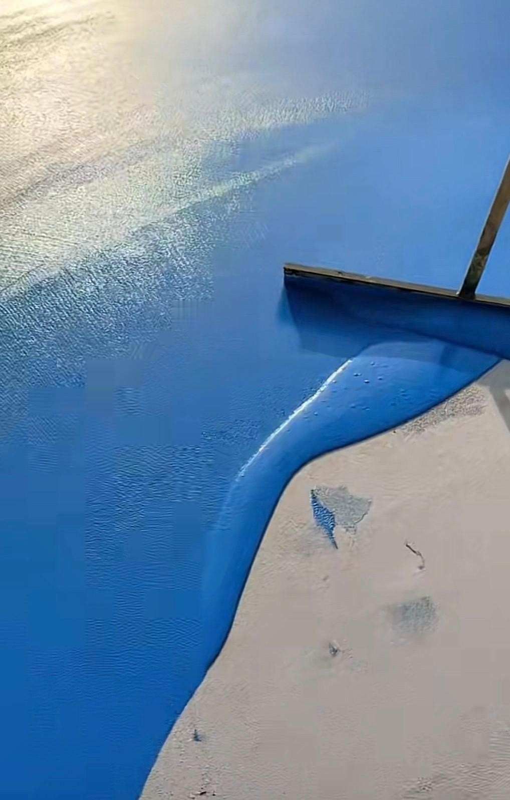 Se extiende pintura azul con un rodillo sobre una superficie blanca, creando un borde liso y curvo.