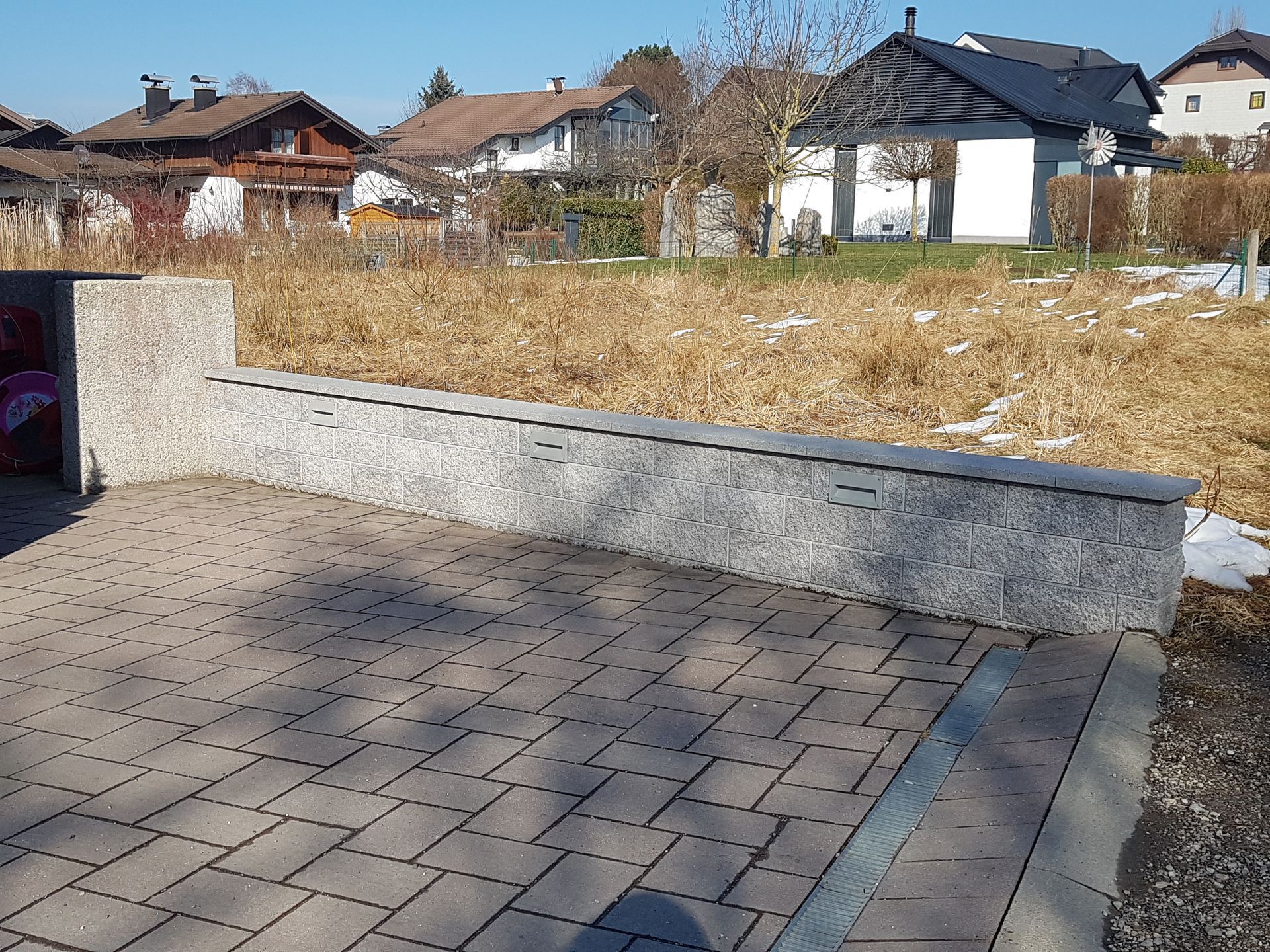 Ein gemauerter Gehweg mit Häusern im Hintergrund