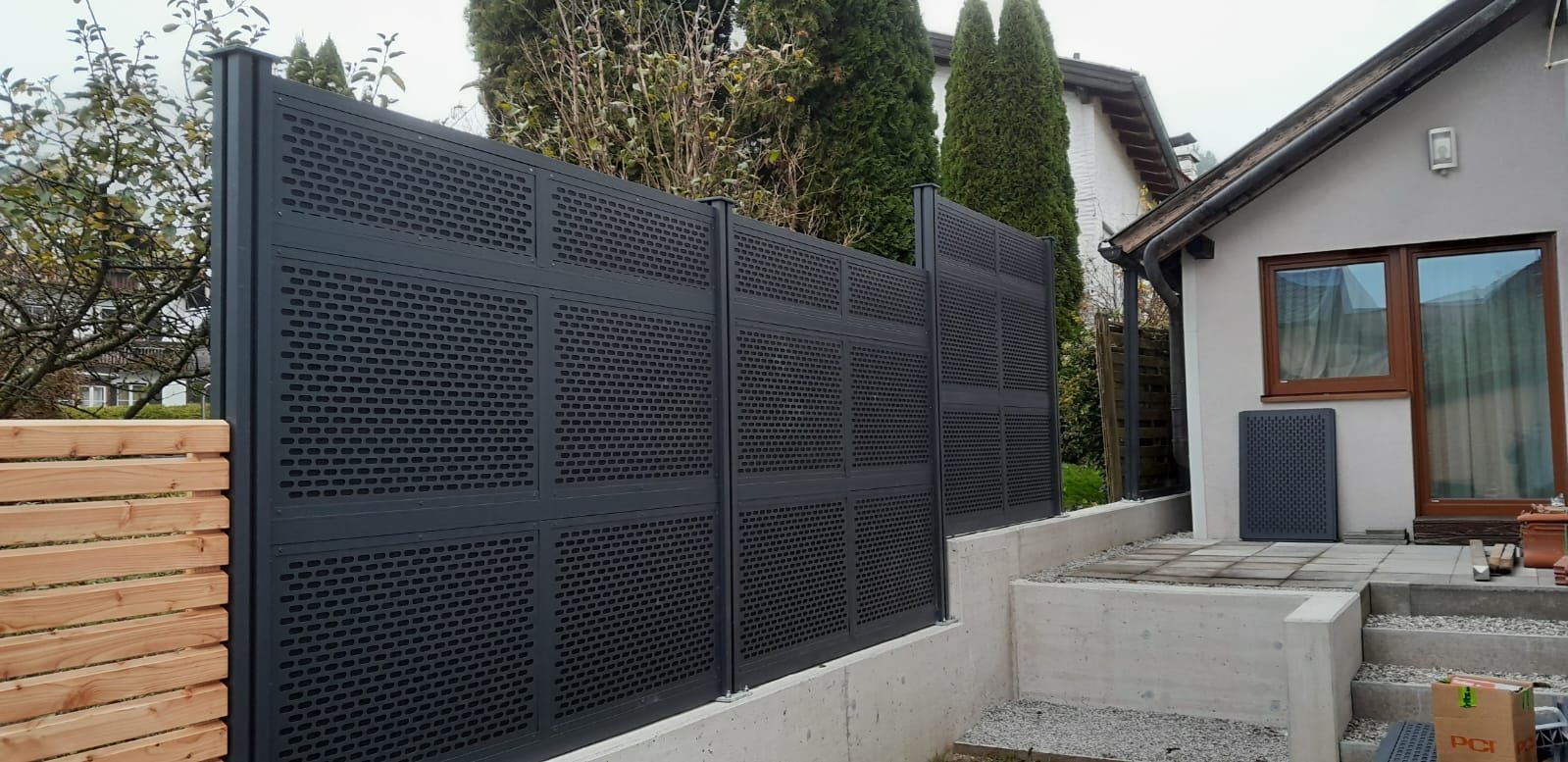 Vor einem Haus steht ein schwarzer Zaun.