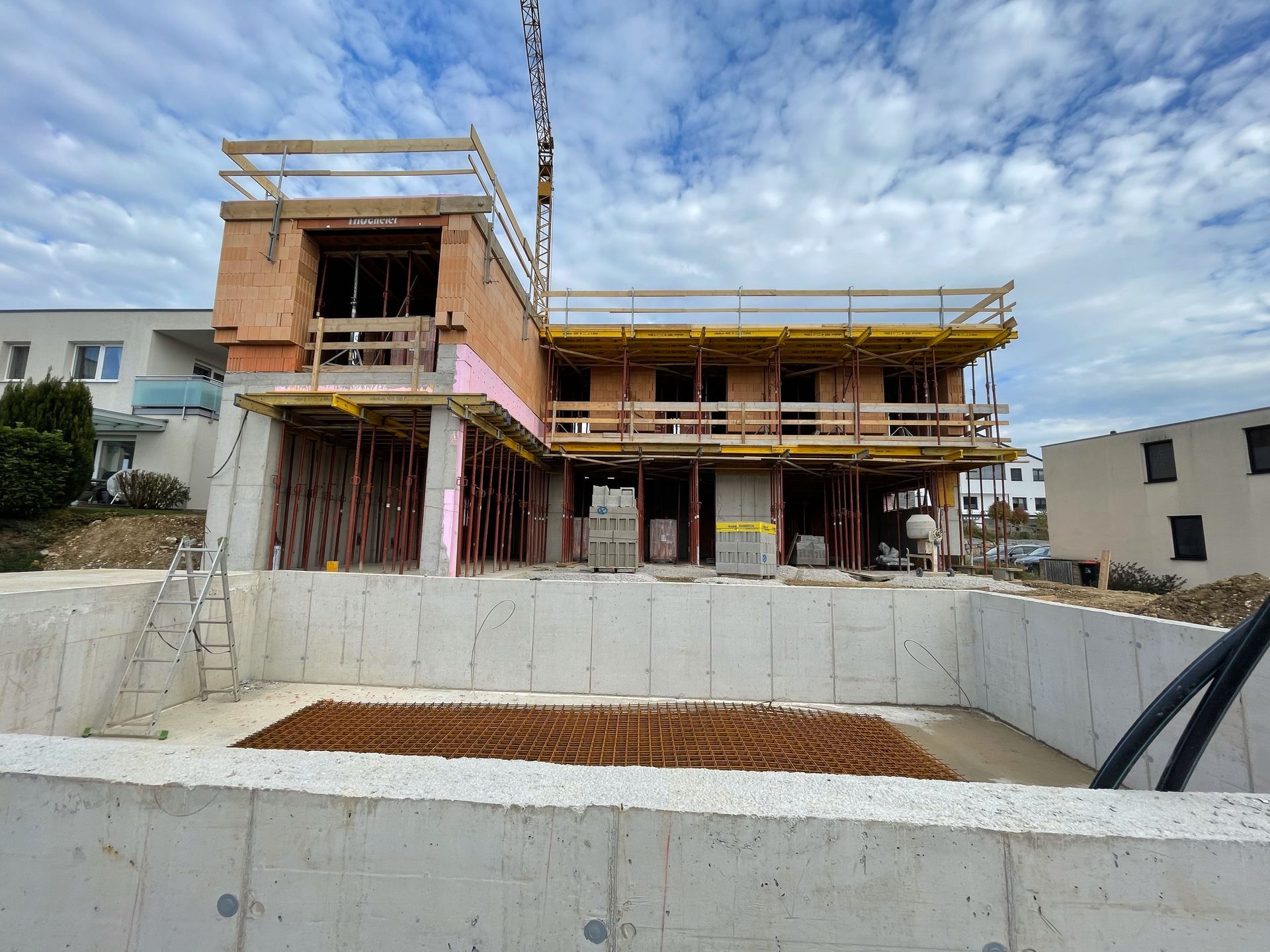 Ein großes im Bau befindliches Backsteingebäude mit einem Swimmingpool davor.