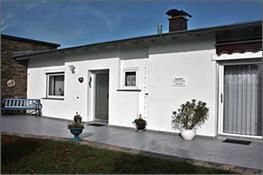 Ein weißes Haus mit einer Terrasse und einer Bank davor.