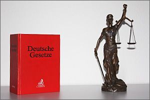 Eine Statue der Gerechtigkeit steht neben einem roten Buch.